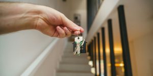 Clés de maison tenues devant une porte, symbolisant la vigilance avant de réserver une location de vacances