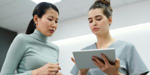 Professionnelle de santé consultant une tablette avec un logiciel de gestion médico-social lors d'une visite à domicile