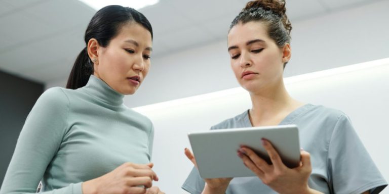 Professionnelle de santé consultant une tablette avec un logiciel de gestion médico-social lors d'une visite à domicile
