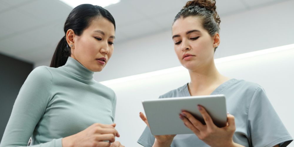 Professionnelle de santé consultant une tablette avec un logiciel de gestion médico-social lors d'une visite à domicile